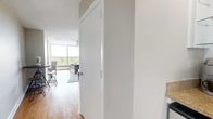 Located at 1860 Fairfield Ave in Shreveport, Louisiana, this efficiently designed studio offers a single-floor layout that maximizes every square foot. The open living area is anchored by warm hardwood flooring that runs throughout, complemented by neutral-toned walls and a textured ceiling. A floor-to-ceiling sliding glass door floods the space with abundant natural light and opens to a balcony with elevated views of the surrounding treetops and neighborhood below, creating a bright and airy atmosphere.

The living area is thoughtfully arranged to accommodate both lounging and dining, with space for a sofa, coffee table, and a bistro-style high-top table and stools. A full wall of built-in white cabinetry with drawers provides generous storage without sacrificing floor space. A dedicated built-in desk nook with overhead cabinetry and a granite-style countertop offers a functional workspace tucked neatly into the room. A ceiling fan adds comfort overhead.

The bathroom is clean and well-appointed, featuring light tile flooring, a pedestal sink, a medicine cabinet mirror, and a full tub-shower combination with white tile surround. The overall design of the space is practical and cohesive, making it well-suited for efficient, comfortable living.