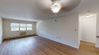 Located at 601 Park St in Bordentown, NJ, this two-story, one-bedroom, one-bathroom unit offers a well-organized and functional layout spread across two levels. The main level is anchored by a generous combined kitchen and living room area. The kitchen is well-equipped with warm, rich wood cabinetry, granite-style countertops, a subway tile backsplash, and black appliances including an electric range, built-in microwave, dishwasher, and refrigerator. A large window above the kitchen area allows natural light to fill the space. The open living room features hardwood-style flooring and a ceiling fan, creating a bright and comfortable gathering area. A staircase connects the main level to the upper floor, where the spacious primary bedroom is found. The bedroom is finished with plush carpeting, a large multi-pane window overlooking greenery, a baseboard heating unit, and a closet. The full bathroom includes a pass-through window that reveals in-unit laundry, adding convenience to everyday living. Throughout the unit, baseboard heating is present in multiple rooms, and the clean, neutral color palette creates a cohesive and inviting atmosphere.