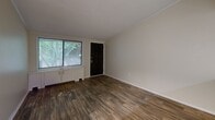 Located at 7250 Campbellton Rd SW in Atlanta, GA, this one-bedroom, one-bathroom unit offers a efficiently designed single-floor layout. Wood-style flooring runs consistently throughout the space, providing a cohesive and easy-to-maintain aesthetic.

The living room is a bright, open area featuring a large window that frames views of surrounding greenery, allowing natural light to fill the room. A bold black front door adds a distinct design contrast to the neutral walls.

The kitchen is well-equipped with ample white cabinetry, dark granite-style countertops, a mosaic tile backsplash, and black appliances including a refrigerator and electric range. Track lighting illuminates the workspace, and a peninsula counter provides additional prep space.

The bedroom is a comfortable, quiet retreat with its own window overlooking lush outdoor greenery, wood-style flooring, and a textured ceiling with a flush ceiling light.

The bathroom features a full-size tub-shower combination with chrome fixtures and clean white surroundings. A dedicated laundry area includes wire shelving and washer/dryer hookups alongside the water heater. A connecting hallway ties all rooms together in a straightforward, functional layout.