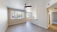 This single-story residence offers a thoughtfully designed layout that balances comfort and functionality throughout. The open living area serves as the heart of the home, featuring light wood-look flooring, a ceiling fan with light fixture, and large windows fitted with horizontal blinds that invite abundant natural light while maintaining privacy. A pass-through counter with a sink connects the living space seamlessly to the kitchen.

The galley-style kitchen is well-equipped with white shaker cabinetry, light quartz countertops, a classic white subway tile backsplash, and a full suite of stainless steel appliances including a gas range, over-the-range microwave, and refrigerator. The clean, bright aesthetic carries throughout.

The bedroom is finished with plush carpeting, a ceiling fan, and a sliding glass door with vertical blinds offering direct outdoor access and natural light. Built-in shelving niches in the entry hallway provide convenient storage, complemented by closet space nearby.

The bathroom features wood-look tile flooring, a single-sink vanity with light countertops, a tiled shower-tub combination, and a well-lit mirror. A dedicated laundry room accommodates a full-size washer and dryer side by side, adding everyday practicality. Neutral wall tones and consistent flooring create a cohesive, move-in-ready environment throughout the space.