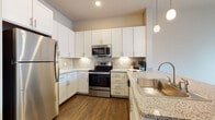 Located at 1161 3rd Ave E in Bradenton, Florida, this well-appointed single-floor residence combines modern design with functional living spaces throughout. The kitchen serves as a standout feature, showcasing crisp white shaker cabinetry, granite countertops, a tile backsplash, and a full suite of stainless steel appliances including a refrigerator, range, and built-in microwave. Elegant pendant lighting hangs above the peninsula, which doubles as a breakfast bar and provides a natural transition into the open dining and living areas. The living and dining spaces feature warm wood-look luxury vinyl plank flooring, creating a cohesive and inviting atmosphere. Bedrooms are finished with plush carpeting and receive generous natural light through large windows dressed with clean white blinds. The bathroom is well-designed with white cabinetry, granite countertops, a large vanity mirror framed by bright overhead lighting, and wood-look flooring that ties in with the rest of the home. Neutral wall tones throughout contribute to a calm, contemporary ambiance, while the consistent use of quality finishes across each room reflects a thoughtfully designed and move-in-ready living space.