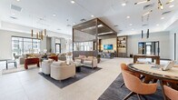 Located at 10141 E Williams Field Rd in Mesa, AZ, this thoughtfully designed amenity lounge spans a generously proportioned single floor, offering a sophisticated and multifunctional community gathering space. The open-concept layout is anchored by large-format stone-look tile flooring that flows seamlessly throughout, unifying each distinct zone within the space.

The main lounge area features multiple curated seating arrangements, including plush neutral sofas and accent chairs, illuminated by striking gold pendant light fixtures and recessed lighting. A wood-slatted architectural partition serves as a design centerpiece, visually defining zones while maintaining an airy, connected feel. Adjacent to the lounge sits a stylish wet bar with counter seating, backlit shelving, and wall-mounted displays.

A dedicated games area houses a solid wood billiards table set beneath dramatic pendant lighting, complemented by built-in shelving with warm accent lighting. Nearby, a lounge nook features a linear fireplace, a wall-mounted TV, and bold terra-cotta accent chairs, creating an intimate retreat within the larger space.

The dining area offers round and rectangular tables beneath oversized pendant lights, positioned near floor-to-ceiling windows that invite natural light. A co-working room with glass partition doors, a round conference table, and exterior views rounds out this well-appointed, design-forward community space.