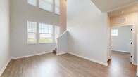 Located in Apopka, Florida, this two-story, two-bedroom, two-bathroom home offers a well-designed layout across two floors. The main level is generously proportioned, anchored by a dramatic living area with soaring double-height ceilings and multiple windows that flood the space with natural light and views of the surrounding greenery. Warm wood-look flooring runs throughout, complementing the home's clean, neutral palette.

The modern kitchen is thoughtfully appointed with white upper cabinetry, grey lower cabinets, white quartz countertops, a herringbone tile backsplash, and a full suite of stainless steel appliances including a range, microwave, dishwasher, and refrigerator. A staircase leads to the upper level, where both bedrooms are situated. The primary bedroom includes a dedicated closet and connects to its own bathroom. Each bathroom features a walk-in glass shower with large-format tile surround, white quartz vanity, and matte black hardware accents. The second bedroom includes a ceiling fan, closet, and access to an exterior door, offering additional versatility. Clean lines, modern fixtures, and a consistent design language give this home a fresh, move-in ready appeal.