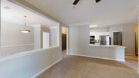 Located at 1400 Mall of Georgia Blvd in Buford, Georgia, this single-floor residence offers a thoughtfully designed open-concept layout that seamlessly connects the kitchen, dining, and living areas. The kitchen is a standout feature, showcasing white shaker-style cabinetry, a green subway tile backsplash, stainless steel appliances including a refrigerator, range, and microwave, and a peninsula with white quartz countertops and an undermount sink — ideal for both cooking and casual dining. The open living area is finished with plush neutral carpeting, crown molding, and a ceiling fan, while natural light flows in through multiple windows. A dedicated dining space features a decorative pendant light and a large window overlooking the greenery outside. The living room opens to an outdoor area through glass French doors, adding an inviting indoor-outdoor connection. The bedrooms are comfortably sized with carpeted floors and windows that bring in natural light. The bathrooms are finished with wood-look luxury vinyl plank flooring, white vanities with clean countertops, framed mirrors, and accessible grab bars. A walk-in closet provides ample storage. The overall palette of soft grays and warm neutrals lends the space a clean, modern, and welcoming ambiance throughout.