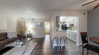 This thoughtfully designed single-story residence offers a functional and stylish layout across five distinct areas: a living room, dining room, kitchen, bedroom, and bathroom. Dark hardwood-style flooring flows seamlessly throughout the home, creating a cohesive and contemporary aesthetic.

The open-concept living room is bright and welcoming, featuring a large window that allows generous natural light to fill the space. It connects naturally to the dining area, which is accented by contrasting gray walls, a ceiling fan, and a cozy nook ideal for intimate gatherings.

The galley-style kitchen is well-equipped, showcasing gray shaker cabinets, white quartz countertops, a mosaic tile backsplash, black appliances including a gas range and refrigerator, and a convenient breakfast bar with bar stools — making it both functional and visually appealing.

The bedroom offers a comfortable retreat with a ceiling fan, a sizable window providing natural light, and a neutral color palette. The bathroom includes a tub/shower combination, a granite-topped vanity, and clean, classic tile work.

Throughout the home, neutral tones, modern finishes, and consistent flooring contribute to a clean, unified ambiance that balances practicality with contemporary style.