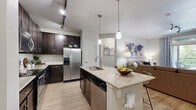 Located at 10320 Commonwealth St in Lone Tree, CO, this thoughtfully designed 3-bedroom, 3-bathroom residence offers a functional open-concept floor plan with contemporary finishes throughout. Light wood-style flooring flows through the main living areas, creating a warm and cohesive aesthetic.

The kitchen is a standout feature, showcasing dark cabinetry, granite countertops, stainless steel appliances including a French door refrigerator, and a center island with pendant lighting and bar seating. It opens seamlessly into the living and dining areas, making the space ideal for everyday living and entertaining. The dining area includes built-in shelving, adding practical storage and character.

The living room is bright and inviting, with sliding glass doors that lead to a private balcony offering outdoor views. The three bedrooms are carpeted for comfort, with the primary bedroom featuring a walk-in closet with built-in shelving. Each bedroom receives ample natural light through generously sized windows.

The three bathrooms are well-finished with dark cabinetry and granite countertops, complementing the overall design palette. A dedicated in-unit laundry room with full-size washer and dryer hookups adds everyday convenience. Neutral wall tones and clean architectural lines give the entire space a modern, move-in-ready feel.