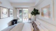 Located at 555 N Spring St in the heart of downtown Los Angeles, this single-floor residence blends contemporary design with thoughtful functionality. The open-concept kitchen is a standout feature, equipped with dark wood cabinetry, white quartz countertops, stainless steel appliances including a range, built-in microwave, dishwasher, and refrigerator, complemented by a patterned tile backsplash. The kitchen flows seamlessly into the living area, which is bathed in natural light and accented with curated artwork and a living green wall panel. Multiple bedrooms offer a calm, neutral palette with clean white walls, soft carpeting, and ample natural light from large windows. The primary bedroom opens directly to a private outdoor patio through sliding glass doors, providing a seamless indoor-outdoor connection. Additional bedrooms feature windows with exterior views and generous space. The bathrooms are finished in crisp white tile, with one offering a glass-enclosed walk-in shower with textured wall tile and mosaic floor tile, and another featuring a soaking tub with glass panel enclosure and built-in open shelving. Throughout the residence, the design emphasizes clean lines, neutral tones, and modern finishes, creating a cohesive and inviting living environment.