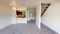 Located at 1948 Cortland in Kent, Ohio, this two-bedroom, one-bathroom two-story home offers a well-organized layout spread evenly across two floors. The main level features a combined kitchen and living room area, where an open pass-through connects the kitchen to the living space. The kitchen is equipped with dark wood cabinetry, a dishwasher, electric range, and tile-style flooring. The living room is carpeted and anchored by a distinctive corner fireplace with a painted brick surround and vertical wood paneling accent, adding character to the space. A large sliding glass door brings in natural light and provides outdoor views. A staircase with dark wood treads, carpeted steps, and open metal railing connects the two floors. The main level also includes a dedicated laundry room with a full-size side-by-side washer and dryer and overhead cabinetry. A hallway leads to the bathroom and additional rooms on the main floor. The bathroom features a tiled tub-shower combination, wood vanity with countertop, and light wood-style flooring. Upstairs, the spacious primary bedroom offers generous proportions with soft carpet flooring and ample wall space. A closet provides dedicated storage. The second bedroom is similarly carpeted and well-sized.