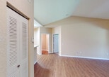 Located at 4495 Emerald Vista in Lake Worth, Florida, this single-story residence offers a well-organized layout designed for comfortable living. The main living area immediately draws attention with its soaring vaulted ceilings and warm wood-look flooring, creating an open and airy atmosphere. A distinctive arched architectural detail with decorative columns frames a large window that offers views of lush tropical palm trees, flooding the space with natural light and enhancing the Florida ambiance.

The galley-style kitchen features white cabinetry, a full suite of white appliances including a refrigerator, range, and microwave, and is complemented by a convenient pass-through breakfast bar that connects seamlessly to the living area. Louvered closet doors near the entry provide practical storage solutions.

The bedrooms are carpeted for comfort and include generous walk-in closet space, with one bedroom featuring double doors leading into a spacious, well-lit walk-in closet. Windows in the bedrooms frame verdant outdoor views, maintaining the home's connection to its tropical surroundings.

The bathroom is equipped with a wide vanity featuring white cabinetry, a large mirror with overhead lighting, and wood-look flooring. Throughout the home, neutral warm-toned walls provide a versatile backdrop, making this Lake Worth property a functional and inviting space.