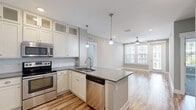 Located at 4310 W Spruce St in Tampa, FL, this well-appointed 2-bedroom, 3-bathroom unit offers a thoughtfully designed single-floor layout. The open-concept kitchen and living area serve as the heart of the home, featuring warm wood-look vinyl plank flooring throughout. The kitchen is a standout, equipped with stainless steel appliances including a French door refrigerator, electric range, and built-in microwave. White shaker cabinetry with glass-front upper cabinets, a decorative wine rack, subway tile backsplash, and a peninsula with pendant lighting and gray quartz countertops complete the space. The living area is bright and airy, with a ceiling fan, recessed lighting, and large windows and a glass door providing access to a balcony. Both bedrooms are carpeted and generously sized, each featuring ceiling fans and ample natural light from dual windows. The spacious primary bedroom connects to an en-suite bathroom with large-format stone tile flooring, a wide vanity with dark countertops, and a glass-enclosed walk-in shower with mosaic tile flooring and full stone tile surround. Neutral gray walls and clean white trim carry throughout, creating a cohesive and modern aesthetic. Two closets provide additional storage throughout the unit.