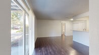This 2-bedroom, 1-bathroom single-floor unit offers a practical and comfortable layout designed to maximize its efficient footprint. Rich, dark hardwood-style flooring runs consistently throughout the space, creating a cohesive and polished look from room to room. The living area is bright and open, benefiting from large floor-to-ceiling windows and a sliding glass door fitted with vertical blinds, allowing generous natural light and views of the surrounding outdoor greenery. A textured ceiling adds dimension overhead.

The galley-style kitchen is clean and functional, featuring white cabinetry with updated hardware, white appliances including a range and refrigerator, light countertops, and a single-basin sink. A pass-through counter connects the kitchen to the main living area, enhancing the open feel.

The spacious primary bedroom offers a ceiling fan with light fixture and natural light from a window with outdoor views. A second bedroom mirrors this setup with its own ceiling fan and window. The primary bedroom includes dual closets with built-in shelving rods, providing ample storage. An additional closet is accessible from the hallway.

The bathroom is well-appointed with a white vanity, light countertop, and a full tub-shower combination with tiled surround and chrome fixtures. The entrance and hallway connect all areas of the unit smoothly, completing this thoughtfully organized layout.