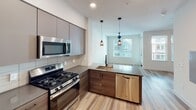 Located at 1921 Union St in Anaheim, California, this single-floor residence offers a thoughtfully designed layout with a clean, contemporary aesthetic. The kitchen is a standout feature, showcasing a two-tone cabinetry scheme that pairs smooth gray upper cabinets with warm walnut-toned lower cabinets. Stainless steel appliances — including a gas range, over-the-range microwave, refrigerator, and dishwasher — provide a fully equipped cooking space. A large-format tile backsplash and dark quartz-style countertops add texture and sophistication, while a peninsula with a single-basin sink and elegant pendant lighting creates a natural transition into the open living area. Light wood-look flooring flows seamlessly throughout the space, enhancing the sense of openness and continuity. The living area is airy and bright, benefiting from a large window that draws in natural light, complemented by a ceiling fan with a built-in light fixture. The bathroom is finished in a similarly modern style, featuring a wood-toned vanity with a gray countertop, a large wall mirror with lighted bar fixture, and a combined tub and shower enclosure with clean white tile. Recessed lighting and light wood-look flooring carry through the cohesive design. Overall, the space presents a fresh, move-in-ready environment with modern finishes at every turn.