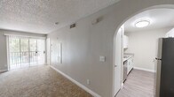 This single-floor residence offers a clean, functional layout designed for comfortable everyday living. The spacious living area is a standout feature, highlighted by plush carpet flooring, a ceiling fan, a textured ceiling, and a corner fireplace that serves as a natural focal point. Large sliding glass doors flood the space with natural light and provide access to an outdoor area, enhancing the open feel of the room. A graceful arched opening connects the living area to the kitchen, creating a cohesive flow between the two spaces. The kitchen is well-appointed with white shaker-style cabinetry, wood-toned laminate countertops, a stainless steel sink, and hardwood-style flooring, offering a bright and practical workspace. The bedroom is a comfortable retreat, featuring soft carpet, a window dressed with blinds that brings in natural light, and a ceiling fan for added comfort. The bathroom is neatly finished with a white vessel sink, wood-toned vanity, a full tub and shower combination with clean white tile surround, and a large mirror. Throughout the space, neutral tones and consistent finishes contribute to a cohesive and inviting ambiance.