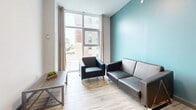 Located at 131 University Ave W in Waterloo, Ontario, this 2-bedroom, 1-bathroom unit offers a well-organized layout across a single floor. Light wood-style flooring runs throughout the space, contributing to a bright and cohesive aesthetic.

The living room features floor-to-ceiling windows that flood the area with natural light and offer views of the surrounding Waterloo cityscape. A teal accent wall adds a pop of colour, while the open layout comfortably accommodates seating and a coffee table.

The kitchen is well-equipped with stainless steel appliances, including a full-size refrigerator and range, complemented by granite countertops, a breakfast bar, and ample upper cabinetry in a warm two-tone finish. The teal accent wall carries through from the living area, creating visual continuity.

The primary bedroom is a comfortable size, featuring a large window with urban views and light-filtering curtains. The second bedroom includes a built-in closet alcove, offering practical storage. Both rooms are finished with the same light wood flooring found throughout the unit.

The bathroom is clean and functional, featuring a white vanity with under-cabinet storage, a mirror, and a shower-tub combination. The unit also includes a hallway that connects the rooms efficiently. This space is ideally situated near the University of Waterloo.