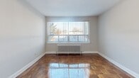 Located at 650 Woodbine Ave in Toronto's vibrant East End neighbourhood, this one-bedroom, one-bathroom unit offers a well-organized and functional layout across a single floor. The entrance opens into a bright hallway with light-toned flooring, connecting seamlessly to the various rooms throughout the unit. Three closets provide ample storage throughout the space. The combined dining and living area is a standout feature, showcasing beautifully polished parquet hardwood floors that add warmth and character. Large windows allow generous natural light to pour in, offering pleasant outdoor views, while a classic cast-iron radiator underscores the building's enduring construction. The kitchen is thoughtfully updated with crisp white shaker-style cabinetry, a marble-look subway tile backsplash, light stone countertops, and a full suite of stainless steel appliances, including a fridge, stove, built-in microwave, and dishwasher. A peninsula counter adds both prep space and a casual dining option. The generously sized bedroom features the same gleaming parquet floors, a large window with outdoor views, and a mirrored closet. The bathroom is finished with wood-look wall tiles, a white vanity, and a tub-shower combination with a glass panel enclosure.