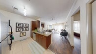This single-floor residence offers a thoughtfully designed open-concept layout that seamlessly connects the kitchen, dining, and living areas. The kitchen is well-equipped with rich medium-toned wood cabinetry, granite countertops, stainless steel appliances including a gas range and built-in microwave, and a peninsula with a double sink — ideal for both cooking and casual entertaining. Light tile flooring runs through the kitchen, transitioning to warm wood-style flooring throughout the living and dining spaces.

The living room is bright and inviting, featuring large sliding glass doors dressed with sheer curtains that allow generous natural light while offering outdoor access. Crown molding and a ceiling fan add refined detail to the space. The dining area comfortably accommodates a full table and chairs, positioned to take advantage of the open flow.

The bedrooms are comfortably sized, each featuring wood-style flooring, large windows with sheer curtains, and neutral wall tones that create a calm, restful atmosphere. The bathrooms are finished with tile flooring, rich wood vanity cabinetry, white countertops, and well-lit mirrors. One bathroom includes a soaking tub, while another features a walk-in shower, providing functional variety throughout the residence.