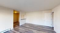 This single-floor residence at 12 Damon Ave in Trenton, NJ offers a well-organized layout with multiple rooms connected by a straightforward floor plan. Throughout the unit, durable wood-style plank flooring in a warm gray-brown tone provides a cohesive look and easy maintenance.

The living area features neutral cream-toned walls and a built-in pass-through opening that connects directly to the kitchen, promoting an open sightline between the two spaces. Baseboard heating units are present along the walls, ensuring consistent warmth. The kitchen is galley-style, equipped with gray shaker cabinetry, granite-look countertops, stainless steel appliances including a refrigerator and gas range, and a window that brings in natural light.

The bedrooms are generously proportioned with the same wood-style flooring, neutral walls, and windows fitted with blinds. Baseboard heaters are present in the bedrooms as well, adding functional comfort. One bedroom receives noticeable natural light, casting bright streaks across the floor.

The bathroom features a full soaking tub with an overhead shower, surrounded by large-format marble-patterned tile that extends fully up the walls. A frosted window above the tub allows natural light while maintaining privacy. The overall ambiance of the space is clean, updated, and move-in ready.