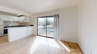 Located at 5201 East 2nd Street in Tucson, Arizona, this thoughtfully designed one-bedroom, one-bathroom unit offers a bright and efficient single-floor layout. Light wood-style flooring runs throughout the entire space, creating a clean and cohesive aesthetic. The open-concept kitchen and living area form the heart of the unit, where the kitchen is outfitted with white shaker cabinetry, dark countertops, a white tile backsplash, and a full suite of stainless steel appliances including a refrigerator, stove, and dishwasher. A peninsula with additional counter space connects the kitchen to the living area, which benefits from abundant natural light streaming in through a large sliding glass door that opens to a private balcony with views of the surrounding Tucson neighborhood and mountain backdrop. A ceiling fan provides additional comfort in the living area. The bedroom offers a comfortable footprint, featuring a window with outdoor views, painted brick accent walls, and a double-door closet for ample storage. The bathroom is finished with a white tiled tub and shower combo. Throughout, the unit maintains a clean, minimalist palette of whites and neutrals, lending the space a fresh, move-in-ready appeal.