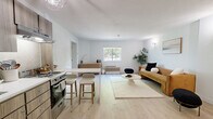 Located at 1151 E Main St in Meriden, Connecticut, this one-bedroom, one-bathroom residence offers a thoughtfully designed single-floor layout with a clean, modern aesthetic throughout. The open-concept kitchen and living area anchors the home, featuring light hardwood flooring, crisp white walls, and abundant natural light streaming through large windows. The kitchen is outfitted with warm wood-toned cabinetry, stainless steel appliances including a full-size refrigerator and range, and a breakfast bar with seating — ideal for casual dining. The living area flows seamlessly from the kitchen, providing a comfortable and airy setting. The generously sized primary bedroom offers plush carpeting, a soft neutral palette, and a bold accent wall that adds visual depth. A wall-mounted HVAC unit ensures year-round comfort, while a large window brings in natural light. The bedroom connects conveniently to a dedicated dressing area with ample storage space. The bathroom presents a striking contrast with dark marble-look tile flooring, marble-accented wall tiles, a combined tub and shower, and a dark wood vanity with a clean white countertop, delivering a bold yet refined finish to the space.