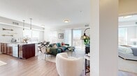 This single-floor residence offers a thoughtfully designed layout across two bedrooms and two bathrooms, making efficient use of its space while maintaining a comfortable, open feel. The open-concept living, dining, and kitchen area forms the heart of the home, where light hardwood-style flooring, crown molding, and large windows create a bright, welcoming atmosphere. A balcony access point off the living room extends the space outdoors, enhancing the sense of openness.

The kitchen is a standout feature, equipped with rich cherry wood cabinetry reaching to the ceiling, stainless steel appliances, a white tile backsplash, and a generous granite-topped island with an undermount sink—ideal for both cooking and casual dining. The adjacent dining area benefits from a corner window arrangement, flooding the space with natural light and offering outdoor views.

The primary bedroom is a comfortable retreat, featuring plush carpeting, a wide picture window with expansive views, and a closet. The second bedroom is similarly appointed with soft neutral tones. Both bathrooms are finished with wood cabinetry, granite or dark stone countertops, and tub-shower combinations with hardwood-style flooring. A central hallway with recessed lighting and crisp white panel doors connects the rooms, contributing to the home's clean, modern aesthetic.