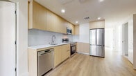 Located at 7050 Hawthorn Ave in Hollywood, Los Angeles, this penthouse unit offers a thoughtfully designed 3-bedroom, 3-bathroom layout across a single floor. Light wood flooring runs throughout the space, creating a warm, cohesive aesthetic that ties each room together.

The open-concept living, dining, and kitchen area serves as the heart of the home. The contemporary kitchen is outfitted with light wood cabinetry, white quartz countertops, a subway tile backsplash, and a full suite of stainless steel appliances, including a refrigerator, range, microwave, and dishwasher. Recessed lighting illuminates the space cleanly and efficiently.

Each of the three bedrooms features crisp white walls, light wood flooring, and windows that invite natural light and outdoor views of the surrounding neighborhood. The bedrooms are serviced by dedicated closets, providing ample storage throughout.

The three bathrooms are finished in neutral tones with large-format tile and glass-enclosed walk-in showers. One bathroom features a vessel sink atop a wood vanity, adding a refined touch to its clean design. In-unit laundry adds further convenience to this well-appointed home. The overall ambiance is modern, bright, and move-in ready.