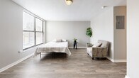 Located at 722 Walnut St in Kansas City, MO, this one-bedroom, one-bathroom unit offers a compact yet well-organized layout across a single floor. The space is finished with durable hardwood-style flooring throughout, lending a cohesive and clean aesthetic to every room.

The generously sized bedroom serves as the heart of the unit, easily accommodating a full sleeping area, seating, and a workspace. Large windows allow ample natural light to pour in while offering views of the surrounding cityscape. A wall-mounted HVAC unit ensures year-round comfort. Three closets provide a notable amount of storage throughout the unit.

The kitchen features rich, dark wood cabinetry that extends to the upper walls for maximized storage, complemented by a tile backsplash and full-size appliances including a refrigerator, electric range, and microwave. The layout is efficient and practical for everyday use.

The bathroom includes a warm wood vanity topped with a clean white countertop and an integrated sink, with a mirror above. Neutral tones carry throughout, giving the space a calm and functional character. A dedicated utility room and hallway round out the floor plan, keeping essentials neatly tucked away. This unit is ideal for those seeking a straightforward, functional living space in an urban Kansas City setting.
