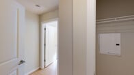 This single-floor residence offers a cohesive and functional layout with consistent finishes throughout. The kitchen serves as a central highlight, featuring a peninsula with dark granite countertops, an undermount sink, and light maple cabinetry extending to the ceiling for ample storage. Stainless steel appliances, including a refrigerator, range, and built-in microwave, are complemented by a herringbone-patterned tile backsplash. A circular flush-mount light fixture illuminates the space.

Light hardwood-style flooring flows throughout the main living areas and into the bedrooms, creating visual continuity. One bedroom features a window with horizontal blinds allowing natural light, while another room benefits from a skylight panel overhead. A dedicated closet area with built-in shelving provides organized storage.

The hallway connects rooms with a clean, neutral palette of warm beige tones and white trim. The full bathroom features dark tile flooring, a tub-shower combination with tiled surround, a maple vanity with granite countertop, an undermount sink, and a large mirror with a multi-bulb light fixture above. The overall design is practical and uniform, with a calm, neutral aesthetic throughout.