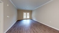 Located at 440 Cane Hill Rd in Nashville, TN, this well-appointed one-bedroom, one-bathroom residence offers a thoughtfully designed layout across a single floor. The open-concept kitchen and living area serves as the heart of the home, featuring rich hardwood-style flooring, crown molding, and a set of French doors that flood the space with natural light and provide access to a private balcony overlooking a green yard area. The kitchen is equipped with stainless steel appliances, white shaker cabinetry, a subway tile backsplash, granite countertops, and a curved peninsula with pendant lighting and a double sink — ideal for both cooking and casual dining. The generously sized bedroom is finished with plush carpet, a ceiling fan, and a window with natural light. It connects directly to a walk-in closet outfitted with wire shelving and hanging rods, offering ample storage. The bathroom features large-format tile flooring, a white vanity with granite countertops, and a framed mirror with overhead lighting. Neutral tones throughout the space create a clean, cohesive aesthetic that is both modern and inviting.