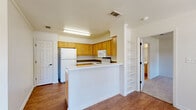This single-story 2-bedroom, 2-bathroom residence offers a practical and comfortable layout across a thoughtfully organized floor plan. The living room serves as the heart of the home, featuring large windows that flood the space with natural light, soft carpeting, and a ceiling fan overhead. Wood-look flooring flows through the main areas, providing a warm, cohesive feel throughout.

The kitchen is designed for functionality, featuring warm honey-toned cabinetry with ample storage, white appliances including a range, microwave, dishwasher, and refrigerator, complemented by tile backsplash accents and a double-basin sink. A breakfast bar peninsula connects the kitchen to the living area, making it ideal for everyday use.

Both bedrooms are carpeted and bright, each equipped with ceiling fans and windows that invite natural light. The primary bedroom offers a generous footprint with comfortable proportions. The two bathrooms mirror each other in style, outfitted with light wood cabinetry, white countertops, and wood-look flooring — one featuring a walk-in shower and the other a full tub-shower combination.

A dedicated laundry room with overhead cabinetry and washer/dryer hookups adds practical convenience. The hallway ties the layout together seamlessly, making this a well-rounded, move-in-ready home.