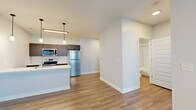 Located at 3680 Paramount Dr in West Lafayette, Indiana, this thoughtfully designed one-bedroom, one-bathroom unit offers a clean, contemporary aesthetic throughout its efficiently utilized single-floor layout. Light wood-tone flooring flows seamlessly across every room, complementing the bright, neutral-toned walls and white trim that give the space an open, airy feel.

The kitchen serves as a central highlight, featuring dark espresso cabinetry, a classic white subway tile backsplash, quartz countertops, and a full suite of stainless steel appliances including a refrigerator, electric range, and microwave. A peninsula island with an undermount sink and pendant lighting above adds both functionality and style, opening directly to the living area.

The bedroom is a comfortable, well-proportioned room with a ceiling fan, a large window with blinds providing natural light, and direct access to a closet. The bathroom is finished with a dark-cabinet floating vanity, quartz countertop, a large mirror with accent lighting, and a tiled shower. A dedicated laundry area houses a stacked Whirlpool washer and dryer unit, offering added convenience. A hallway connects all rooms in a practical, efficient flow, completing this well-appointed modern residence.