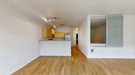 Located at 4744 12th Avenue Northeast in Seattle's vibrant University District, this one-bedroom, one-bathroom unit offers a thoughtfully designed open-concept layout that maximizes its efficient footprint. Warm light wood flooring flows throughout the entire unit, creating a cohesive and inviting atmosphere.

The combined living, dining, and kitchen area forms the heart of the home. The kitchen is well-appointed with light maple cabinetry, granite-style countertops, and a full suite of stainless steel appliances including a refrigerator, electric range, over-the-range microwave, and dishwasher. A peninsula counter provides additional prep space and serves as a natural divider between the kitchen and living area. Track lighting illuminates the space effectively.

The bedroom is bright and comfortable, featuring large windows that bring in generous natural light, along with a sliding glass door that opens directly onto a private patio overlooking a landscaped courtyard with raised garden beds. Two closets provide ample storage throughout the unit.

The bathroom is clean and modern, featuring a wood-toned vanity with a undermount sink, a solid surface countertop, a large mirror, and wood-look tile flooring. A hallway connects the main living area to the bedroom and bathroom, completing this well-organized and functional layout.