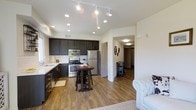 This single-story residence offers a well-designed 2-bedroom, 2-bathroom floor plan with an open-concept layout that seamlessly connects the kitchen and living areas. The kitchen is a standout feature, showcasing dark espresso cabinetry that contrasts beautifully with light countertops and a classic white subway tile backsplash. Stainless steel appliances, including a gas range, microwave, and refrigerator, provide a modern, functional workspace. A undermount sink with a sleek faucet completes the setup. Track lighting and recessed ceiling lights illuminate the kitchen and main living area effectively. Rich wood-tone laminate flooring runs throughout the main living space, adding warmth and visual continuity. A hallway leads to the two bedrooms and bathrooms, offering a defined separation between living and sleeping areas. The open layout between the kitchen and living room creates a spacious, airy feel, ideal for everyday living and entertaining. Clean white walls and neutral tones throughout contribute to a bright, welcoming ambiance. The overall design balances contemporary style with practical functionality.