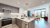 This thoughtfully designed one-bedroom, one-bathroom residence offers a seamless blend of modern aesthetics and functional living across a single floor. The open-concept kitchen and living area serves as the heart of the home, featuring sleek taupe cabinetry, a large peninsula with a double sink and white quartz countertops, stainless steel appliances including a built-in microwave and dishwasher, and a subway tile backsplash. The layout flows naturally into the dining area and living room, where floor-to-ceiling windows and a glass balcony door flood the space with natural light and frame sweeping urban skyline views. Wide-plank wood-tone flooring runs throughout, tying each area together cohesively. The bedroom is a comfortable retreat, highlighted by an oversized window with city views and clean white walls. The spa-inspired bathroom features large-format marble-look tile flooring, a glass-enclosed shower, a soaking tub, a floating dual vanity, and direct access to a well-organized walk-in closet. A dedicated in-unit laundry area with a full-size washer and dryer adds everyday convenience. Recessed lighting throughout enhances the bright, airy ambiance of this polished urban residence.
