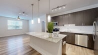 Located at 14700 Torrey Chase Blvd in Houston, TX, this well-appointed single-story home offers 2 bedrooms and 2 bathrooms with a thoughtfully designed open-concept layout. The kitchen serves as the heart of the home, showcasing dark espresso cabinetry, a full suite of stainless steel appliances, white subway tile backsplash, and a generous granite-topped island illuminated by elegant pendant lighting and track lighting overhead. Light wood-look flooring flows seamlessly through the main living areas, adding warmth and continuity. The primary bedroom features its own dedicated bathroom equipped with a granite-topped dark vanity, a glass-enclosed walk-in shower with marble-style tile surround, and matching wood-look flooring. The primary suite also connects to a spacious walk-in closet outfitted with wire shelving, hanging rods, and built-in lower shelving for organized storage. The second bedroom is finished with plush carpet, a ceiling fan, and a window allowing natural light. A second carpeted bedroom and an additional bathroom with a tub/shower combination provide comfortable accommodations for guests. Both bedrooms include dedicated closet space, and the home's neutral color palette creates a clean, contemporary ambiance throughout.