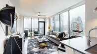 Located in the heart of Midtown Atlanta at 1400 W Peachtree St NW, this contemporary high-rise unit offers five bedrooms and two bathrooms across a single thoughtfully designed floor. A welcoming hallway adorned with hardwood-style flooring and a decorative area rug connects the various rooms with ease.

The living area is a true highlight, featuring expansive floor-to-ceiling windows that frame breathtaking panoramic views of the Atlanta skyline. A ceiling fan, balcony access, and an abundance of natural light create an open and airy atmosphere. The kitchen is well-appointed with sleek white cabinetry, a glass tile backsplash, stainless steel appliances including a gas range, and dark quartz countertops — ideal for both everyday cooking and entertaining.

The primary bedroom continues the floor-to-ceiling window theme, offering sweeping city views alongside a generous walk-in closet. Additional bedrooms are equally well-sized, each with closet space. Both bathrooms feature marble-style tile, modern white vanities with dark countertops, and clean, upscale finishes — one with a soaking tub and shower combination, the other with a glass-enclosed walk-in shower. The overall aesthetic throughout is modern and cohesive, with hardwood-style flooring tying each space together.
