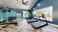 Located at 1000 Park Place Ave in Morrisville, NC, this fitness center offers a thoughtfully designed exercise room that combines functionality with an energizing aesthetic. The space is characterized by striking teal-painted walls accented with crisp white crown molding and vaulted ceilings, creating a sense of openness and height. A large ceiling fan with dark blades anchors the room overhead, while recessed lighting ensures the space is well-lit throughout.

The herringbone-patterned flooring in warm, neutral tones adds a refined visual element underfoot. Large windows along one wall flood the room with natural light and provide views of the surrounding greenery, enhancing the inviting atmosphere. Full-length wall mirrors on one side expand the sense of space and allow users to monitor their form during workouts.

The exercise room is comprehensively equipped with cardio machines including multiple treadmills and an elliptical trainer, as well as a multi-station cable machine, an adjustable weight bench, a dumbbell rack, and a medicine ball storage rack. This well-rounded selection of equipment supports a variety of workout routines, from cardiovascular training to strength and flexibility work, making it a versatile fitness facility for all experience levels.