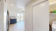 This contemporary 910 square foot space in Kennewick, Washington, showcases a thoughtful two-story design. The ground floor, measuring 450 square feet, features an open-concept layout with a striking kitchen as its centerpiece. The kitchen boasts a two-tone cabinet design, with navy lower cabinets complementing white upper cabinets, creating a visually appealing contrast. Stainless steel appliances and light-colored countertops add to the modern aesthetic.

The upper level, spanning 460 square feet, includes a loft area overlooking the main floor. A standout feature is the sleek black metal railing, which provides safety without obstructing the open feel. A modern pendant light fixture hangs from the ceiling, adding both illumination and style to the space.

The bathroom continues the contemporary theme with a clean, white color palette. It features a bathtub-shower combination with a white curtain, a toilet, and a vanity with a blue base cabinet. Light wood-look flooring runs throughout the space, unifying the design and adding warmth.

Large windows allow ample natural light to flood the interior, enhancing the sense of spaciousness. The overall design emphasizes clean lines, neutral colors, and a harmonious blend of style and functionality, creating an inviting and modern living environment.