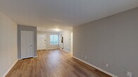 This well-appointed one-bedroom, one-bathroom residence in Philadelphia's 19116 zip code offers a thoughtfully designed single-floor layout. The open living area is anchored by warm hardwood-style flooring and neutral gray walls, creating a bright and welcoming atmosphere. A front entry door with a glass accent panel allows natural light to filter into the space, while a large sliding glass door at the rear of the living room opens to an outdoor view, further enhancing the sense of openness. An arched doorway connects the living area to the kitchen, which features white shaker-style cabinetry, light granite-look countertops, a stainless steel appliance suite including a refrigerator, gas range, and microwave, and a double sink. The generously sized primary bedroom is carpeted for comfort, with a natural window providing pleasant daylight. The full bathroom is finished in crisp white, complete with a tub/shower combination, vanity, and hardwood-style flooring. Three closets offer ample storage throughout, and a dedicated laundry area adds everyday convenience. The consistent neutral palette and clean finishes throughout give this residence a cohesive, move-in-ready character.