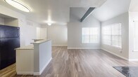 Located at 14135 Champions Dr in Houston, TX 77069, this single-story home offers a well-designed layout with consistent wood-look flooring throughout. The living area is a standout, featuring vaulted ceilings with exposed beams, a ceiling fan, an arched window that invites natural light, and a striking floor-to-ceiling tiled fireplace that serves as a central focal point. The open flow between the living and dining areas creates a sense of spaciousness and connectivity. The kitchen is equipped with white cabinetry, granite-style countertops, a mosaic tile backsplash, and black appliances including a refrigerator, range, microwave, and dishwasher. A peninsula with a breakfast bar provides additional prep space and casual seating, while an adjacent bathroom adds everyday convenience. The bedrooms are comfortably sized, each with ceiling fans, natural light from windows with blinds, and ample closet space. The bathroom features a vanity with a light countertop and cabinetry, connected via a hallway that maintains a clean, neutral aesthetic. Throughout the home, light gray walls and white trim create a bright, cohesive atmosphere that complements the warm tones of the flooring.