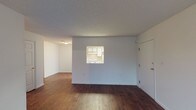 This single-floor unit offers two bedrooms and one bathroom within a well-organized layout. Wood-style flooring runs consistently throughout the living areas and bedrooms, providing a warm, cohesive look. The open living area features neutral gray walls, a textured ceiling, and a pass-through window that connects directly to the kitchen, adding a functional and distinctive architectural detail. A door from the living area leads to a private balcony, allowing natural light to fill the space and offering exterior views.

The galley-style kitchen is efficiently arranged with white cabinetry on both sides, a stainless steel sink, laminate countertops, and white appliances including a range and refrigerator. A hallway leads from the kitchen further into the unit.

Both bedrooms feature the same wood-style flooring and are finished with neutral walls and textured ceilings. Large windows fitted with vertical blinds allow ample natural light and views to the outdoors.

The bathroom includes a tub and shower combination, a vanity with a mirror, and straightforward, functional finishes. Throughout the unit, the design is clean and practical, making it a functional and comfortable living space.