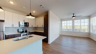 Located in Atlanta, GA, this contemporary single-floor residence offers a thoughtfully designed open-concept layout that seamlessly connects the kitchen, dining, and living areas. The kitchen is a standout feature, equipped with stainless steel appliances including a refrigerator, electric range, and microwave, complemented by a two-tone cabinetry scheme of crisp white upper cabinets and rich dark wood lower cabinets. A large center island with a light quartz countertop and undermount sink adds both functionality and style, illuminated by sleek pendant lighting overhead. Durable wood-look flooring flows throughout the main living areas, while the bright living room benefits from a wall of windows and a ceiling fan, creating an airy, welcoming atmosphere with outdoor views. The bedrooms feature plush carpeting and generous window placement that allows abundant natural light to fill each room. The primary bathroom offers an extended vanity with a white quartz countertop, dark wood cabinetry, a large mirror, and direct access to a walk-in closet with wire shelving. A secondary bathroom provides a tiled soaking tub and shower combination with brushed nickel fixtures and matching wood-tone vanity. Clean lines, neutral tones, and modern finishes are consistent throughout, creating a cohesive and contemporary living environment.