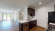 Located at 6900 Bonita Terr in the heart of Los Angeles, CA 90028, this single-floor residence offers a thoughtfully designed layout with contemporary finishes throughout. The kitchen serves as a standout feature, equipped with rich dark-stained cabinetry that extends to the ceiling, crisp white quartz countertops, a subway tile backsplash, and a full suite of stainless steel appliances including a gas range, microwave, refrigerator, and dishwasher. A peninsula with an undermount sink and a professional-style faucet provides additional prep space and a natural connection to the adjacent living area. The open living and dining areas are finished with warm wood-style flooring, recessed lighting, and clean white walls that create a bright, welcoming atmosphere. The bedroom is carpeted for comfort and features a window that frames views of neighboring palm trees and the sunny Los Angeles streetscape, filling the room with natural light. The bathroom is outfitted with white subway tile surrounding a soaking tub with a shower, complemented by brushed nickel fixtures for a clean, modern aesthetic. Throughout the residence, a consistent design language of neutral tones and quality materials delivers a polished and functional living environment.