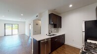 Located at 6900 Bonita Terr in the heart of Los Angeles, CA 90028, this single-floor residence offers a thoughtfully designed layout with contemporary finishes throughout. The kitchen serves as a standout feature, equipped with rich dark-stained cabinetry that extends to the ceiling, crisp white quartz countertops, a subway tile backsplash, and a full suite of stainless steel appliances including a gas range, microwave, refrigerator, and dishwasher. A peninsula with an undermount sink and a professional-style faucet provides additional prep space and a natural connection to the adjacent living area. The open living and dining areas are finished with warm wood-style flooring, recessed lighting, and clean white walls that create a bright, welcoming atmosphere. The bedroom is carpeted for comfort and features a window that frames views of neighboring palm trees and the sunny Los Angeles streetscape, filling the room with natural light. The bathroom is outfitted with white subway tile surrounding a soaking tub with a shower, complemented by brushed nickel fixtures for a clean, modern aesthetic. Throughout the residence, a consistent design language of neutral tones and quality materials delivers a polished and functional living environment.