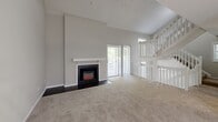 Located in Sandy Springs, GA, this three-bedroom, two-bathroom residence spans three floors, offering a well-organized and functional layout throughout. The main living level is the heart of the home, anchored by a generously sized living room with dramatic vaulted ceilings, a fireplace with a classic white mantle, and sliding glass door access to an outdoor balcony. Natural light filters in through multiple windows, creating a bright and airy atmosphere. A ceiling fan adds comfort to the open upper area that overlooks the living space via a white-railed staircase.

The kitchen is well-appointed with white cabinetry, dark granite-style countertops, a stainless steel gas range, and wood-look flooring. A pass-through window connects the kitchen to the dining area, which features a pendant light fixture.

The primary bedroom is notably spacious, offering large windows with garden views and plush carpeting. The additional bedrooms are comfortably sized, each with natural light and carpeted floors. Two full bathrooms serve the home, one featuring a soaking tub and shower combination with white tile surround, and the other with a granite-topped vanity and tub. Two closets provide ample storage throughout the residence.