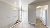 Located at 2167 NE Loop 410 in San Antonio, TX, this two-story, 2-bedroom, 2-bathroom unit offers a functional and clean layout spread across two levels, with the majority of the living space situated on the upper floor. A white-railed staircase with carpeted treads connects the levels, complemented by light-toned hardwood-style flooring and neutral gray walls throughout the main areas, creating a bright and cohesive aesthetic.

The primary bedroom features plush carpeting, a ceiling fan with lighting, and a generously sized window that allows natural light to fill the room. It is accompanied by a spacious walk-in closet with built-in shelving and a full en-suite bathroom boasting dual sinks, a wide vanity with white cabinetry, a large mirror with Hollywood-style lighting, and wood-look flooring. A second full bathroom features a clean white tiled tub-shower combo. The secondary bedroom also offers carpeted flooring and a clean, open feel.

A hallway connects the upper-level rooms, and a balcony accessible from the unit provides outdoor views of the surrounding neighborhood and mature trees. The overall design is clean and neutral, offering a versatile canvas for personalization.