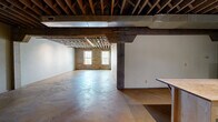 Located on S Buck St in Cincinnati, OH, this distinctive 3-bedroom, 2-bathroom residence showcases an industrial aesthetic rooted in raw, character-rich architecture. The single-floor layout offers a spacious, open feel throughout, anchored by polished and stained concrete floors that run continuously across the living areas. Exposed wooden ceiling joists and beams soar overhead, lending dramatic height and a warehouse-loft sensibility to the space.

The open-concept kitchen is outfitted with stainless steel appliances, light wood cabinetry, a stainless range, microwave, and a large refrigerator, complemented by a butcher block island that adds functional workspace. Original brick walls with multi-pane windows invite natural light into the main living areas, framing views of the surrounding greenery.

Structural concrete columns and visible ductwork reinforce the industrial character throughout the common spaces. The bedrooms feature smooth, neutral-toned walls with the same concrete flooring and exposed ceiling construction. Two closets provide storage, including a walk-in style space with built-in shelving. The two bathrooms contrast in style — one offers a clean white tub-shower combo with brushed nickel fixtures, while the second features a tiled walk-in shower, modern vanity with open shelving, and corrugated metal shower surround details, maintaining the industrial theme.