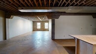 Located on S Buck St in Cincinnati, OH, this distinctive 3-bedroom, 2-bathroom residence showcases an industrial aesthetic rooted in raw, character-rich architecture. The single-floor layout offers a spacious, open feel throughout, anchored by polished and stained concrete floors that run continuously across the living areas. Exposed wooden ceiling joists and beams soar overhead, lending dramatic height and a warehouse-loft sensibility to the space.

The open-concept kitchen is outfitted with stainless steel appliances, light wood cabinetry, a stainless range, microwave, and a large refrigerator, complemented by a butcher block island that adds functional workspace. Original brick walls with multi-pane windows invite natural light into the main living areas, framing views of the surrounding greenery.

Structural concrete columns and visible ductwork reinforce the industrial character throughout the common spaces. The bedrooms feature smooth, neutral-toned walls with the same concrete flooring and exposed ceiling construction. Two closets provide storage, including a walk-in style space with built-in shelving. The two bathrooms contrast in style — one offers a clean white tub-shower combo with brushed nickel fixtures, while the second features a tiled walk-in shower, modern vanity with open shelving, and corrugated metal shower surround details, maintaining the industrial theme.