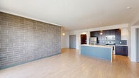 Located at 501 Virginia Ave in Indianapolis, this well-appointed 2-bedroom, 2-bathroom residence offers a thoughtfully designed open-concept layout with modern finishes throughout. The combined living and kitchen area serves as the heart of the home, anchored by a striking full-height brick accent wall that adds texture and character. Light hardwood-style flooring flows throughout the main living spaces, while large sliding glass doors lead to a private balcony with open city views, flooding the area with natural light. The kitchen features dark espresso cabinetry, a subway tile backsplash, stainless steel appliances, and a spacious peninsula with a built-in sink — ideal for both meal prep and casual dining. Pendant lighting overhead adds a contemporary touch. Both bedrooms are carpeted for comfort; the primary bedroom offers a generous footprint with a walk-in closet outfitted with built-in shelving and hanging rods. The second bedroom benefits from dual windows that invite additional natural light. Each bathroom is clean and functional, featuring light wood-style flooring, a full soaking tub with shower, and warm wood-toned vanity cabinetry with a white countertop. Two hallways and two closets round out the practical layout of this modern urban residence.