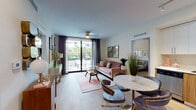 Located in West Miami, FL, this single-floor residence offers a thoughtfully designed layout with contemporary finishes throughout. The open-concept living and dining area features large-format light tile flooring, a ceiling fan, and floor-to-ceiling sliding glass doors that flood the space with natural light and provide direct access to a private balcony overlooking the surrounding greenery. The kitchen is outfitted with stainless steel appliances, sleek white upper cabinetry, warm wood-toned lower cabinets, a white quartz countertop, and track lighting overhead. Two well-appointed bedrooms each feature wood-look tile flooring, generous windows dressed with sheer curtains that invite ample natural light, and ceiling fans for comfort. One bedroom offers an additional window view of lush outdoor surroundings. Both bathrooms are finished with wood-grain wall tiles, soaking tub-shower combinations with rainfall showerheads, modern vanities, and stone-look floor tiles. The unit is tied together by a cohesive mid-century modern aesthetic, neutral warm tones, and quality materials that create a polished, inviting ambiance throughout.
