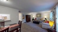 This single-floor residence features two bedrooms and two full bathrooms within a thoughtfully designed layout. The open living area is carpeted and bathed in natural light from large windows dressed with sheer curtains and blinds, creating a bright and welcoming atmosphere. A dedicated dining area adjacent to the living room provides a defined space for meals, complete with a pass-through window connecting to the kitchen.

The galley-style kitchen is outfitted with white cabinetry, light granite-style countertops, a double basin sink, and full suite of white appliances, all set atop wood-look vinyl flooring that extends throughout the wet areas of the home.

The primary bedroom is spacious and carpeted, featuring a ceiling fan with light fixture and access to natural light through a large window. The second bedroom is equally well-proportioned with soft carpet and neutral wall tones. Both bathrooms mirror each other in design, offering white vanity cabinetry, light countertops, a tub-shower combination, and durable wood-look vinyl flooring. Textured ceilings are consistent throughout the home, adding a classic residential character.